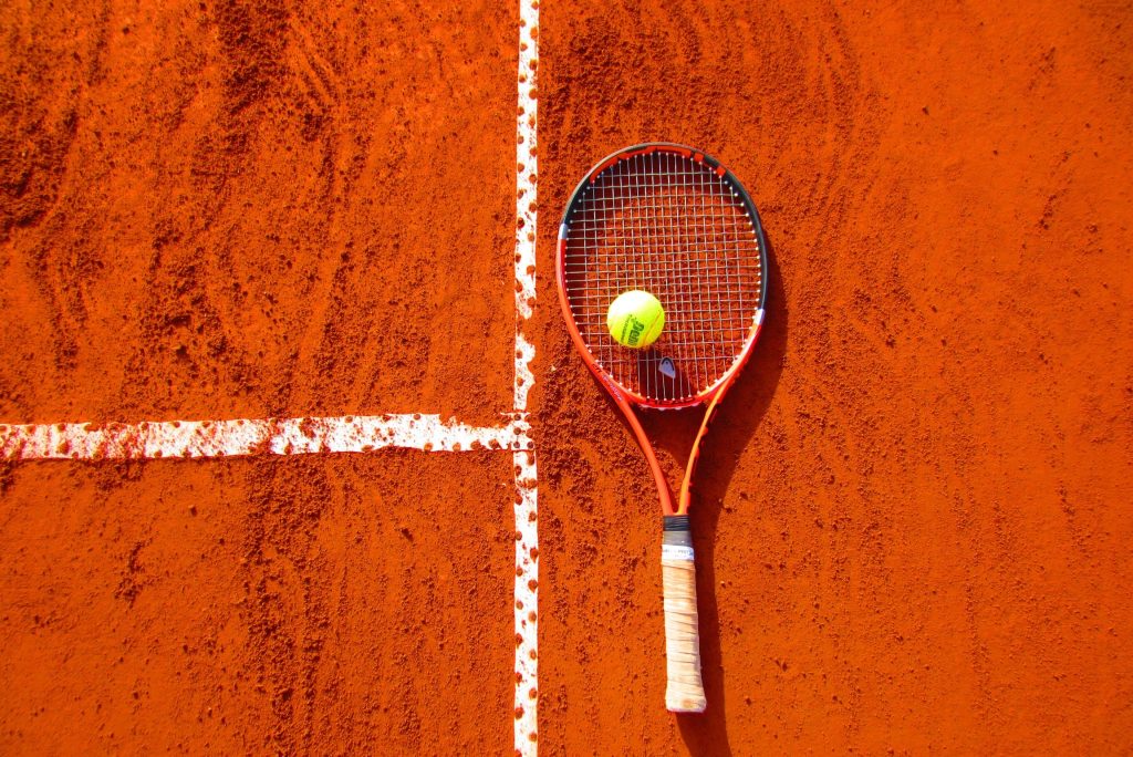 tennis racket and a ball on a red surface